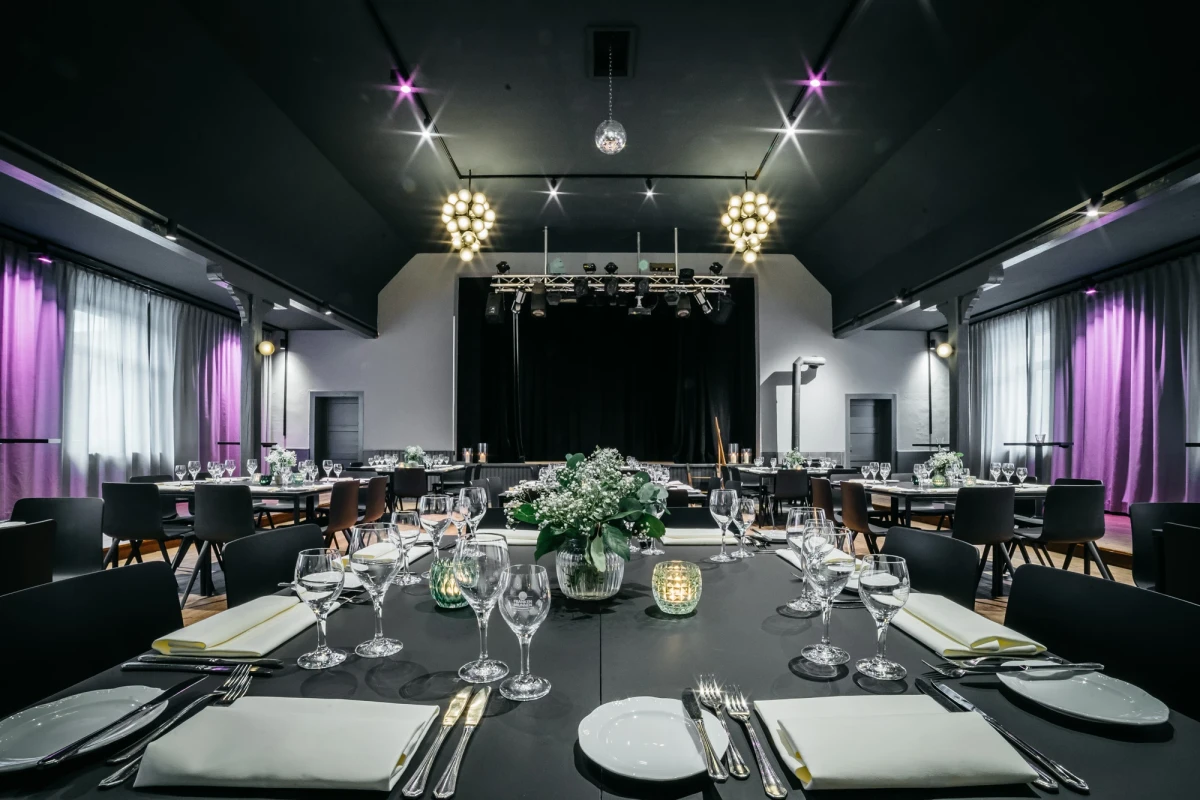 Elegante Eventlocation mit festlich gedeckten Tischen und B&uuml;hne.