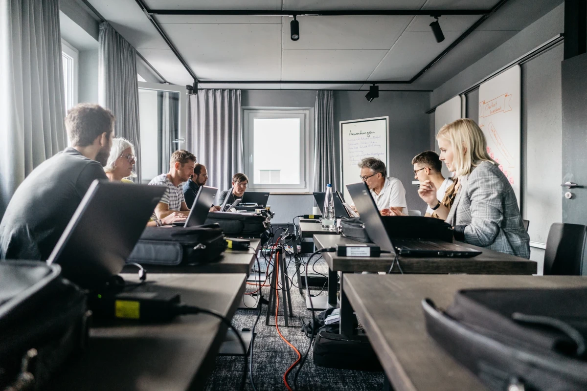Gruppendiskussion in modernem Konferenzraum mit Laptops und Notizen.